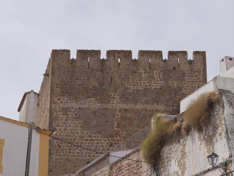 View of the historic stone tower of the Portalegre castle with its crenellated battlements rising above traditional white-walled buildings in Portalegre, Portalegre District, Portugal.