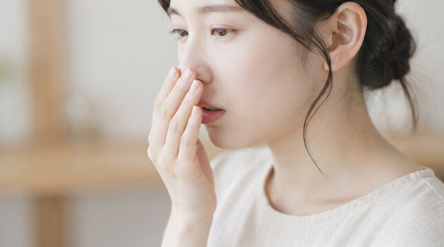 口臭や吐息の匂いを手で覆って気にする女性