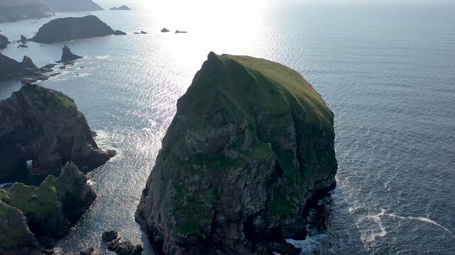 Aerial view of Tormore Island rising from the Atlantic Ocean with rugged cliffs and sparkling water in Ardara, County Donegal, Ireland.