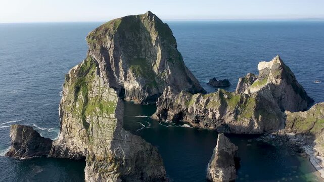 Aerial view of sea stacks at An Port with rugged cliffs and deep blue Atlantic ocean waters in Ardara, County Donegal, Ireland.