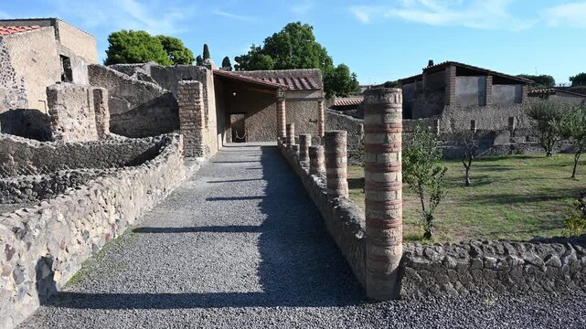 ERCOLANO, ITALY - SEPTEMBER 20, 2026: Panning left to right showing the ancient Roman colonnade and garden courtyard peristyle inside a domus at Herculaneum archaeological site.