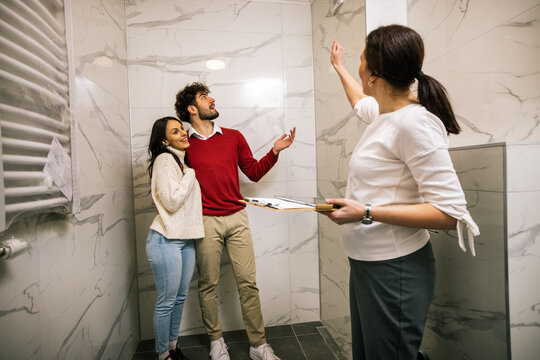 Real estate agent showing modern bathroom features to young couple