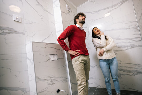 Young couple inspecting bathroom ceiling and walls in new apartment