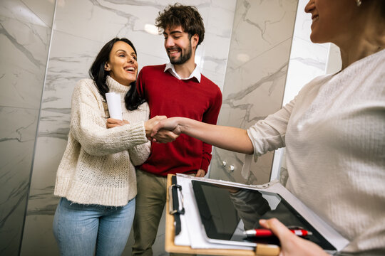 Happy woman holding pen and contract laughing with partner and realtor