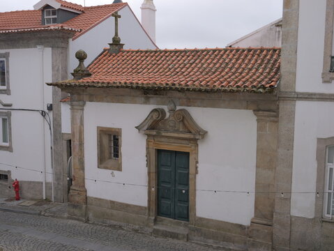 View of a small historic chapel with a stone doorway and terracotta roof in the streets of Covilha, Castelo Branco District, Portugal.
