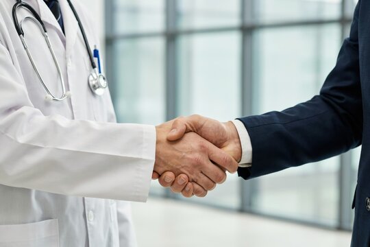 Doctor in white coat shaking hands with a businessman in a suit