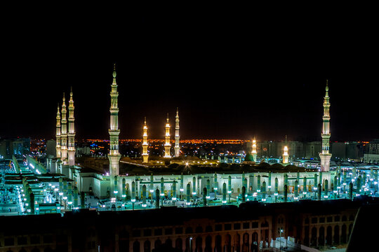 View of the illuminated Al Masjid-e-Nabawi at night with its towering minarets and green dome in Madinah, Al Madinah Province, Saudi Arabia.