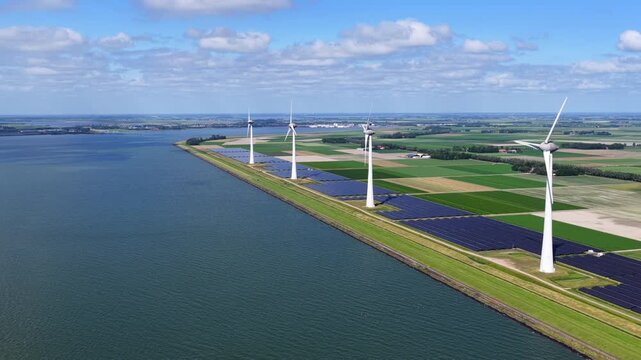 Aerial view of wind turbines and solar panels installed along a dike in Rutten, Flevoland, Netherlands.