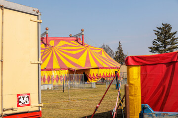 Red and Yellow Circus Tents Behind Picket Fence at Empty Outdoor Carnival Field © Olga