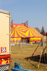 Red and Yellow Circus Tents Behind Picket Fence at Empty Outdoor Carnival Field © Olga