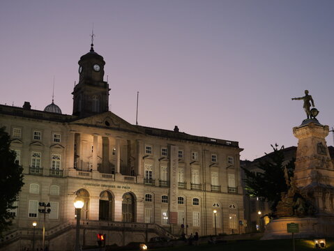 View of Palacio da Bolsa at dusk with its neoclassical architecture and a prominent statue in the foreground in Porto, Porto District, Portugal.