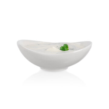 White ceramic bowl of creamy dip with green herb garnish isolated against a clean white background, minimalist food presentation and tabletop still life