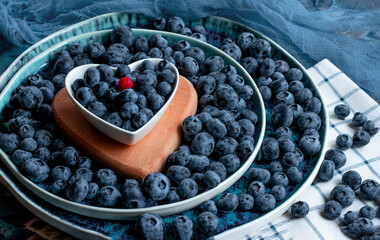 A lot of blueberries on a heart-shaped plate. Blue, healthy summer berries. Blueberry-loving concept. High quality photo © Nataliia