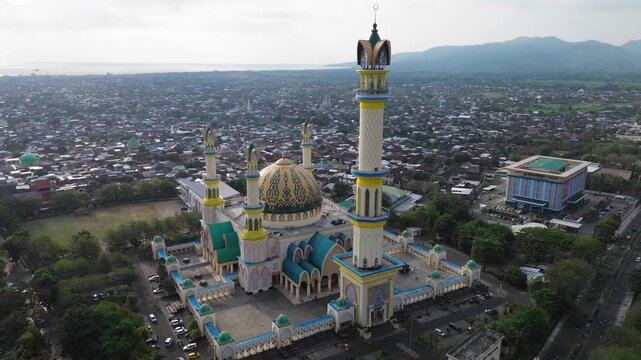 Aerial view of the Islamic Center NTB with its prominent dome and minarets surrounded by the urban landscape of Mataram, West Nusa Tenggara, Indonesia.
