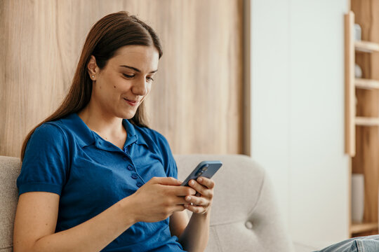 Young woman enjoying social media on smartphone at home