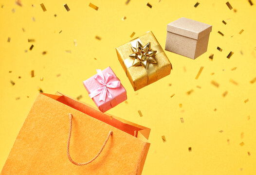 Colorful gift boxes floating out of shopping bag with confetti