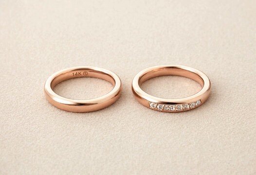 Elegant rose gold wedding rings with small diamond accents on neutral background