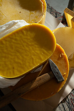 Handmade natural beeswax blocks with a hammer for candle making. Traditional apiiculture craft, beekeeping and DIY wax processing.