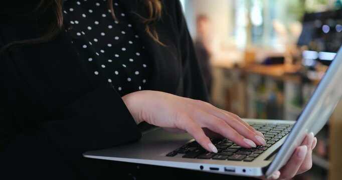 busy female freelancer holding notebook computer types urgent project updates in cafeteria environment, coping with overwork exhaustion and prolonged fatigue during intense corporate routine
