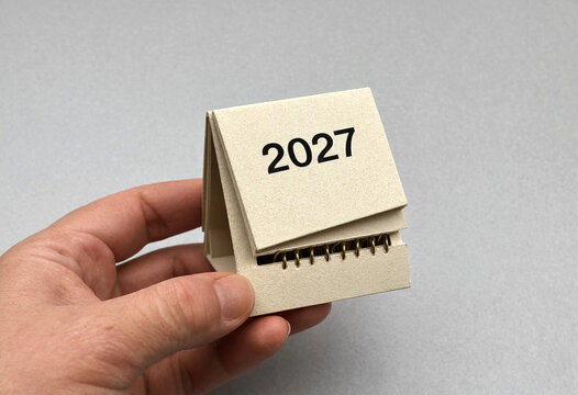Hand holding small spiral notebook labeled with year two thousand twenty seven
