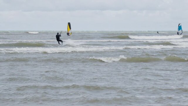 Kitesurfer and windsurfer riding waves in windy sea