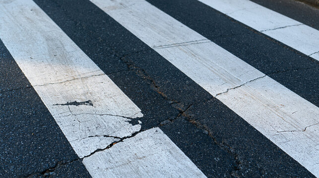 Old damaged pedestrian crossing texture with worn white stripes on cracked asphalt, for game visualization and design, with copy space