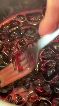 Dark cherries simmering in a metal pan