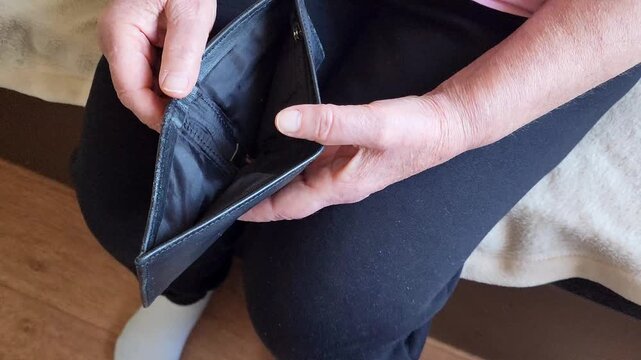 Closeup of senior elderly woman with open empty wallet sitting on sofa at home