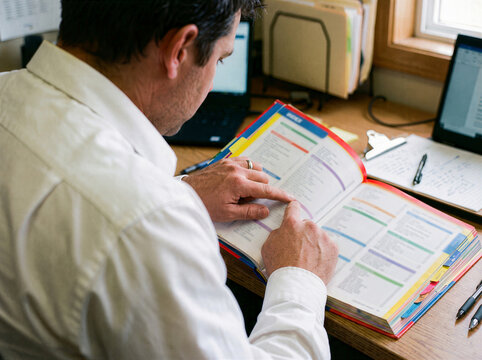 Worker studying first aid manual at office desk for workplace emergency preparedness training