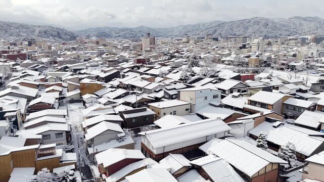 Aerial pan across snow-covered Takayama with the Japanese Alps in the distance, Gifu, Japan.