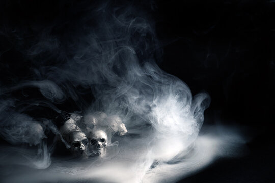 Skulls emerging from dense smoke creating an eerie halloween atmosphere