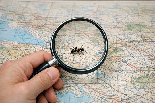 A person examining a map with a magnifying glass, possibly searching for something or planning an expedition