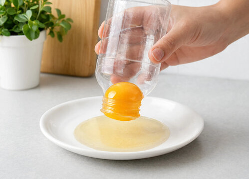 Separating an egg yolk with a clear plastic bottle in a home kitchen