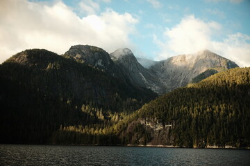 Obraz premium Forested mountains and a dark lake with shoreline buildings
