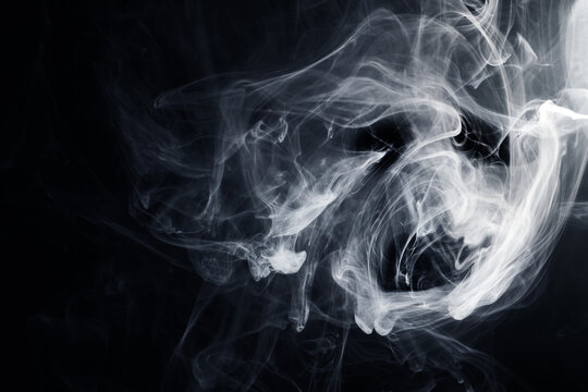 White smoke swirling in abstract shapes on black background