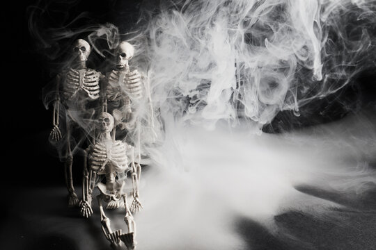 Skeletons emerging from thick spooky smoke