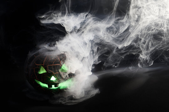 Halloween jack-o'-lantern glowing green with smoke
