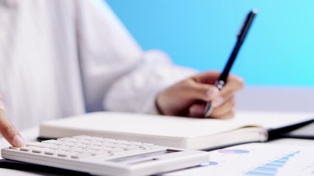 Focused professional woman calculating finance data with pen, notepad, concentrated accountant using calculator, paper, diligent work, bright office