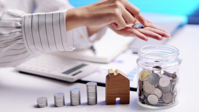 Person saving money home investment budget planning happy feeling showing coins wooden house model finance growth optimistic confident mood