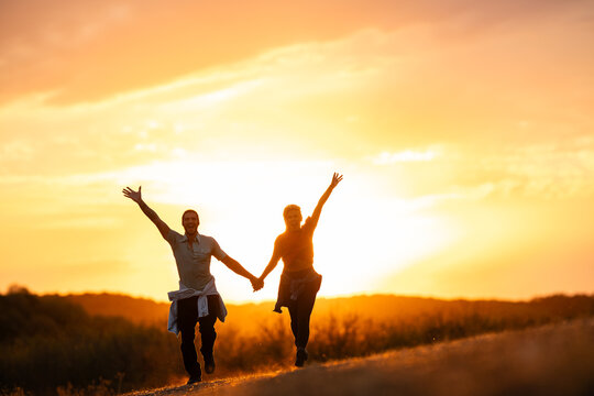 Happy couple running at sunset embracing freedom