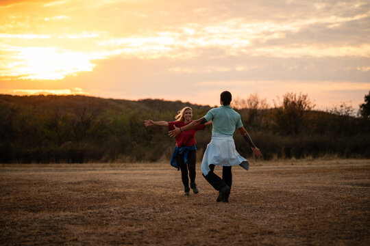 Couple running towards each other embracing freedom and happiness at sunset