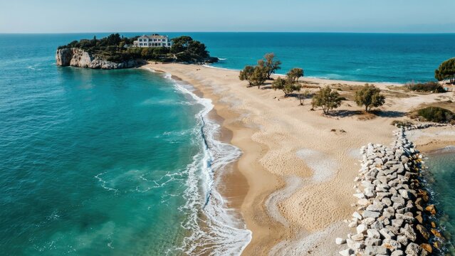 Aerial view of a sandy spit connecting a rocky island with a white villa to the mainland