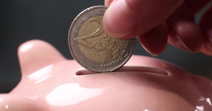 Hand dropping a coin into a slot, saving or financial transaction concept.
