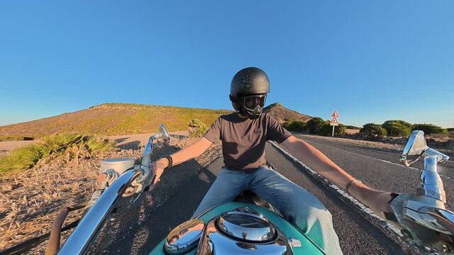Horizontal rear facing action camera view from the motorcycle handlebar as a biker starts a turquoise custom motorcycle at sunset, with natural engine and environmental sounds.