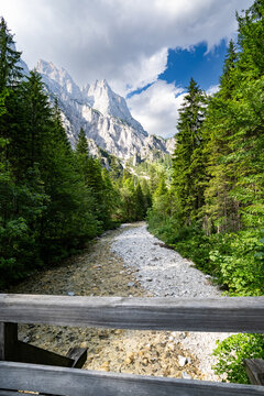 Blick von einer Holzbr&uuml;cke &uuml;ber das steinig-klare Bachbett des Klausbachs auf die Reiteralpe.