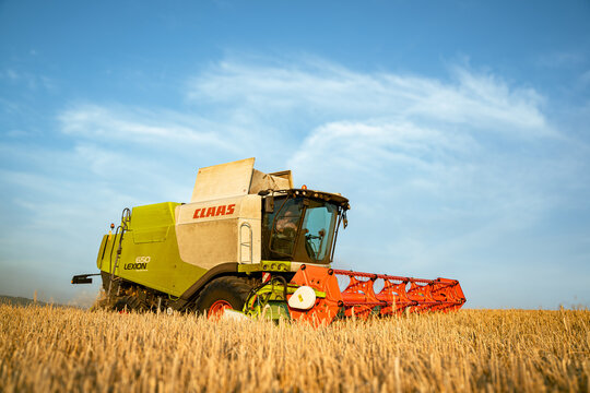 Claas Lexion 650 M&auml;hdrescher im Einsatz bei der Weizenernte auf dem Stoppelfeld im Abendlicht.