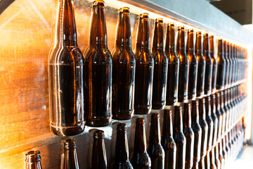 Row of Amber Bottles: A striking composition showcasing a perfectly aligned row of amber glass bottles, filled with a rich, dark liquid, suggesting a craft brewery or artisanal beverage production. © david