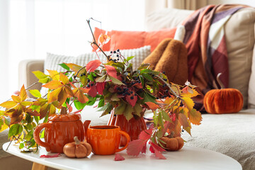 Fototapeta premium Autumn cozy scene with colorful leaves pumpkin teapot and mug on table
