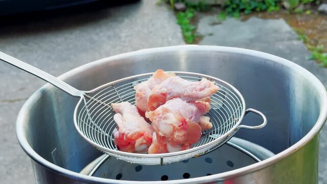Hands Load Raw Chicken Wings Into Fryer Skimmer