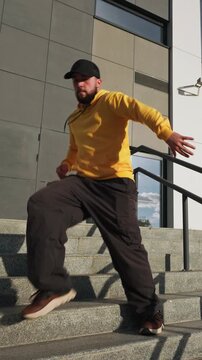 Young man dancing yellow hoodie street dance stairs modern building background slow motion freedom lifestyle footage